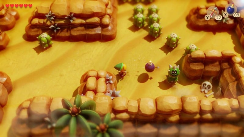 Gameplay from Link's Awakening with Link firing a bomb at an enemy in the desert